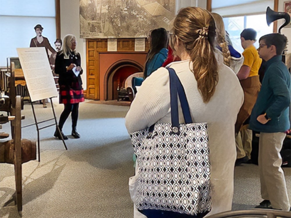 A woman speaking to a group of students in a museum
